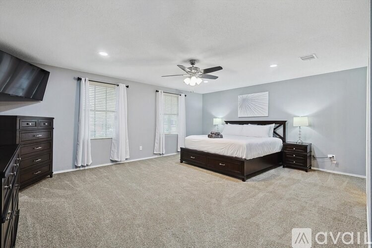 A bedroom with a large bed, a dresser, and a ceiling fan.