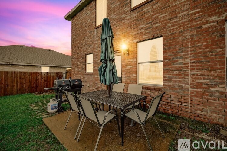 A patio with a table and chairs is set up outside a brick house.