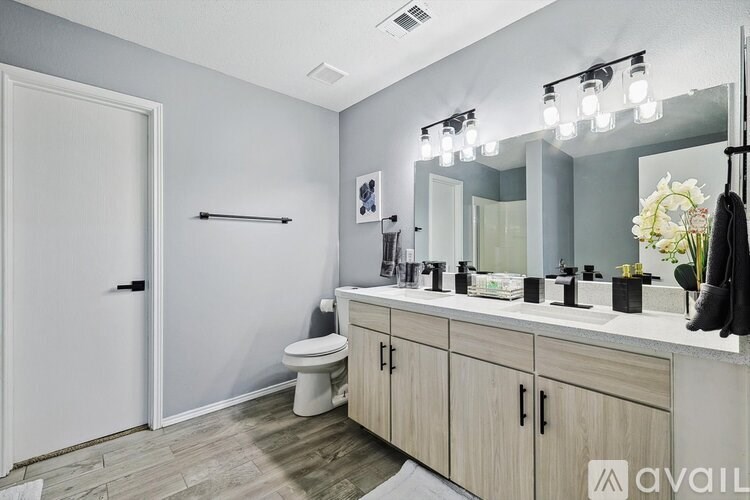 A bathroom with a toilet, sink, mirror, and a white door.