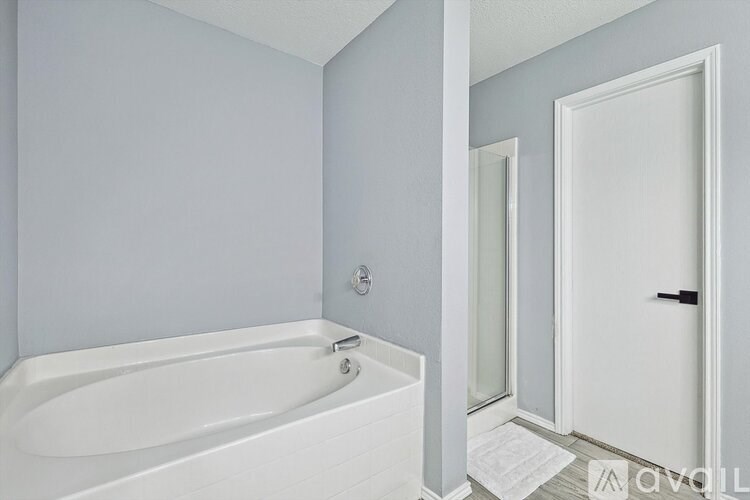 A white bathtub in a bathroom with a white door.