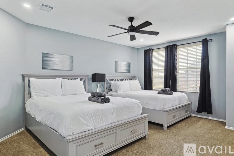 A bedroom with two beds and a ceiling fan.