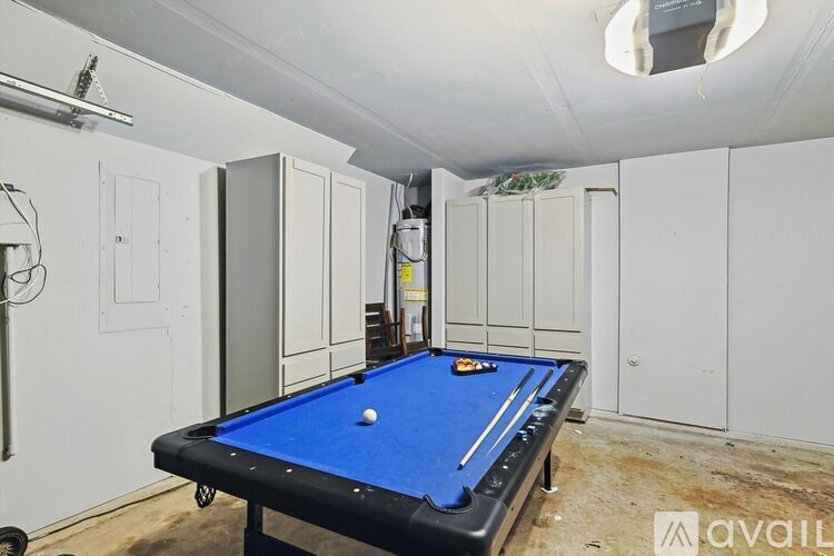 A pool table in a room with white cupboards.