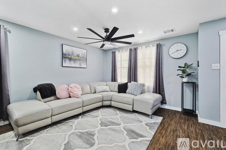 A living room with a white couch and a ceiling fan.
