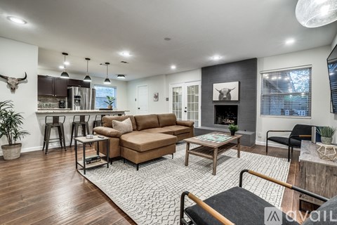 A living room with a brown sofa and a black and white rug.