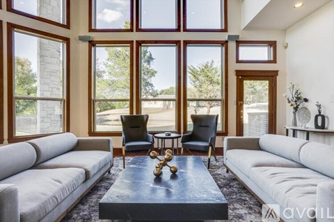 A living room with a grey sofa, a black coffee table, and a glass table with a vase on it.
