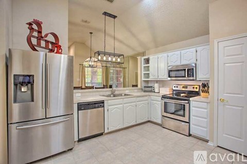 A kitchen with white cabinets and a stainless steel refrigerator.