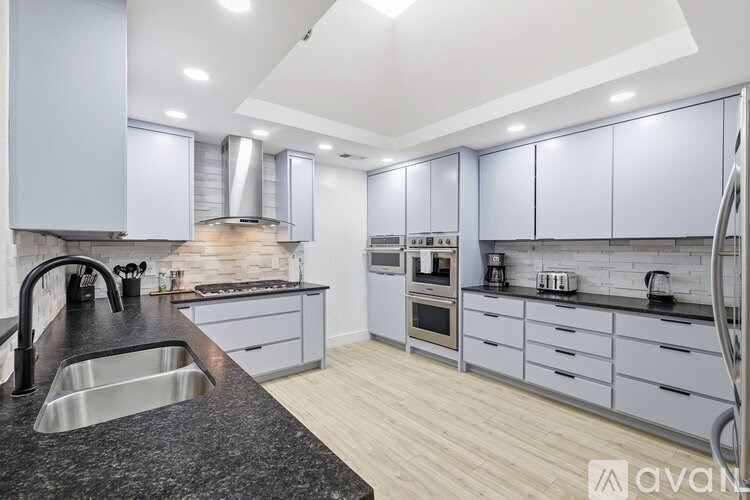 A modern kitchen with stainless steel appliances and wooden floors.