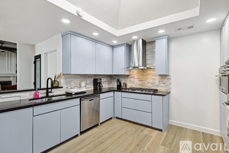 A modern kitchen with a wooden floor and grey cabinets.