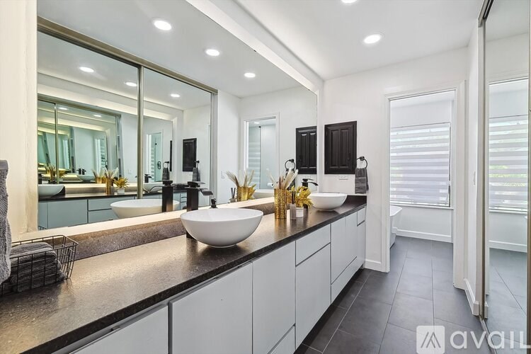 A modern bathroom with a large mirror and a white sink.