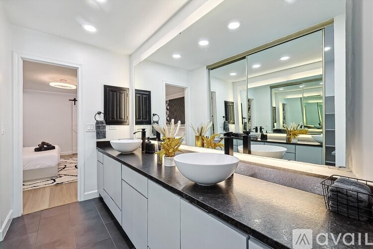 A modern bathroom with a large mirror and a white sink.