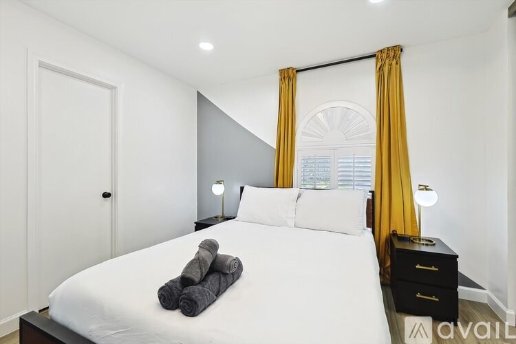 A bedroom with a bed, nightstand, and window with yellow curtains.