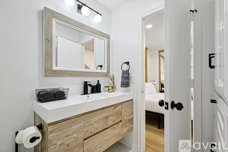 A bathroom with a wooden vanity and a mirror above it.