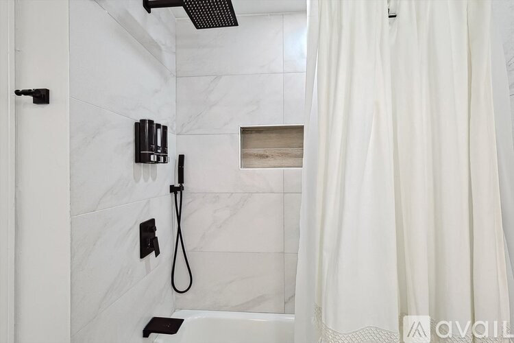A white bathroom with a shower curtain and a black shower head.