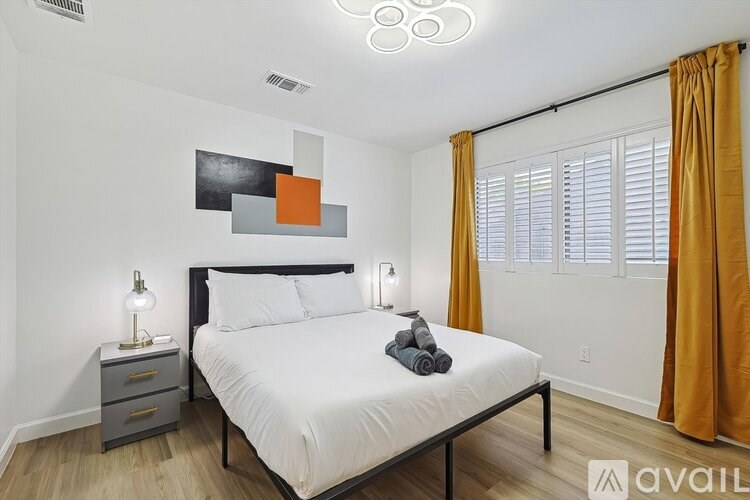 A bedroom with a bed, nightstands, and a painting on the wall.