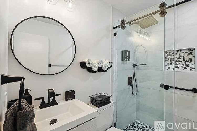A bathroom with a white sink and a glass shower stall.
