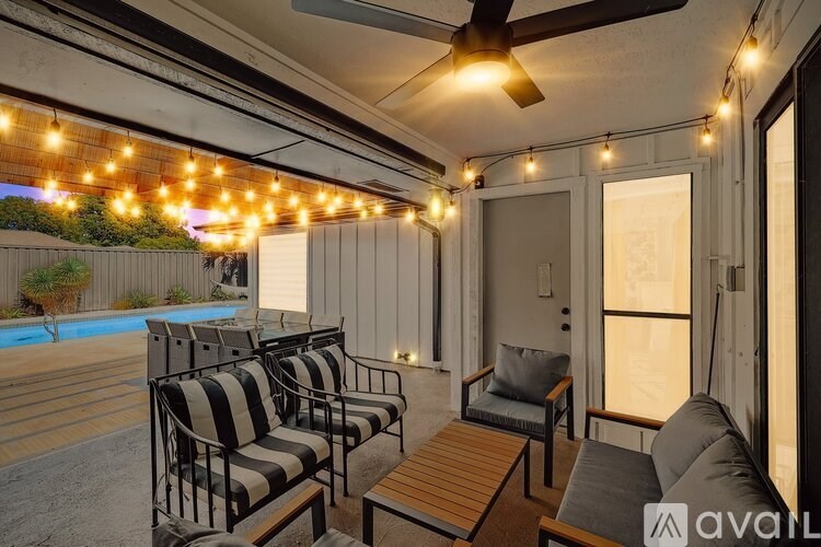 A patio with striped chairs and a ceiling fan.