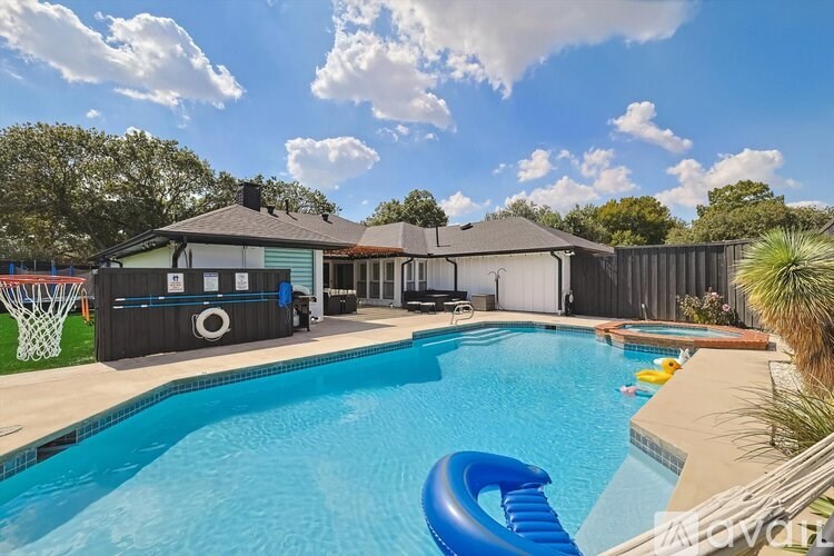 A pool with a slide and a basketball hoop in the backyard.