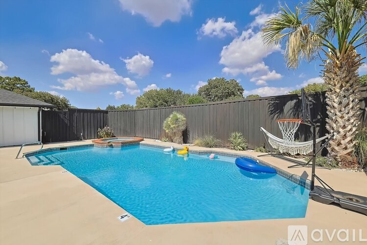 A pool with a basketball hoop and a palm tree.