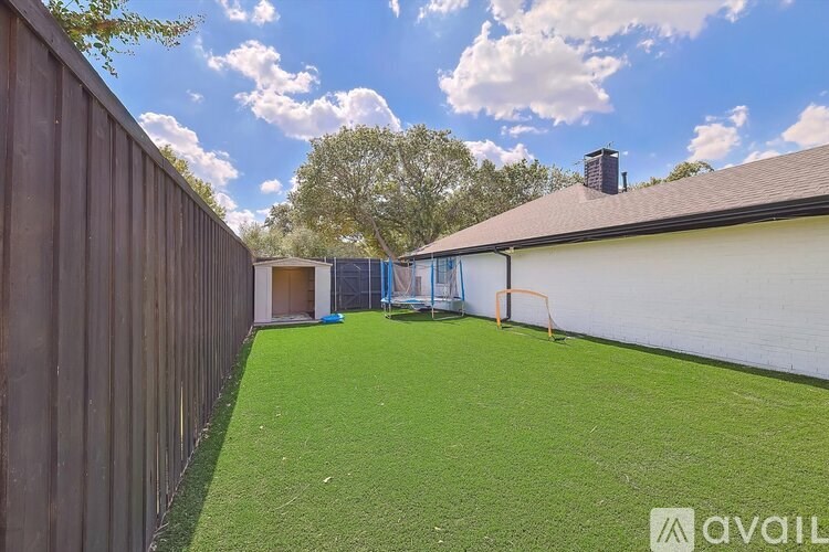 A backyard with a green lawn and a wooden fence.