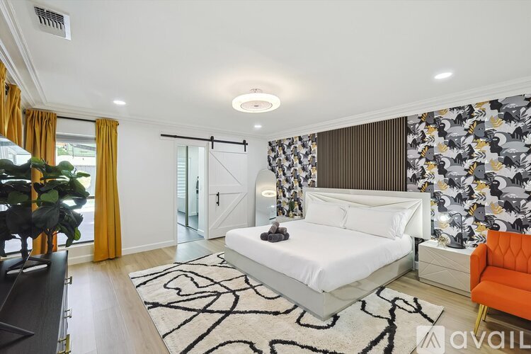 A bedroom with a white bed and orange chair.