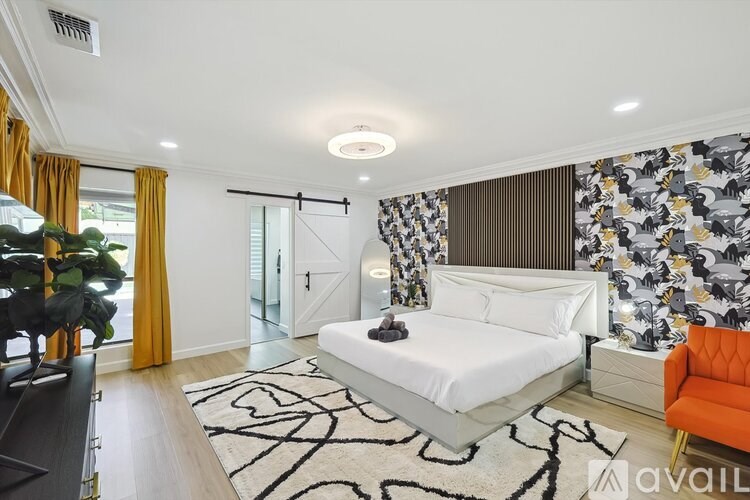 A bedroom with a white bed and orange chair.