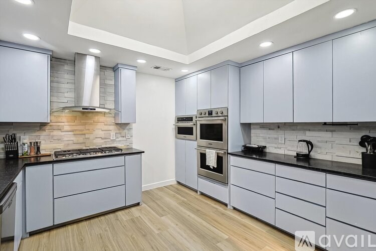 A modern kitchen with a stone backsplash and wooden flooring.