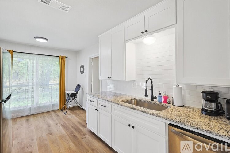 A kitchen with white cabinets and a granite countertop.