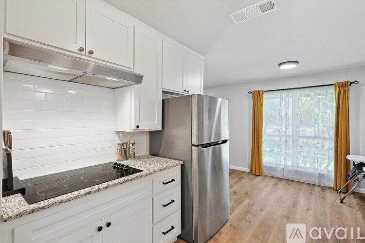 A kitchen with white cabinets and a stainless steel refrigerator.