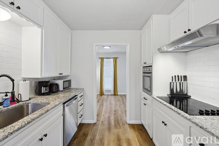 A kitchen with white cabinets and a wooden floor.
