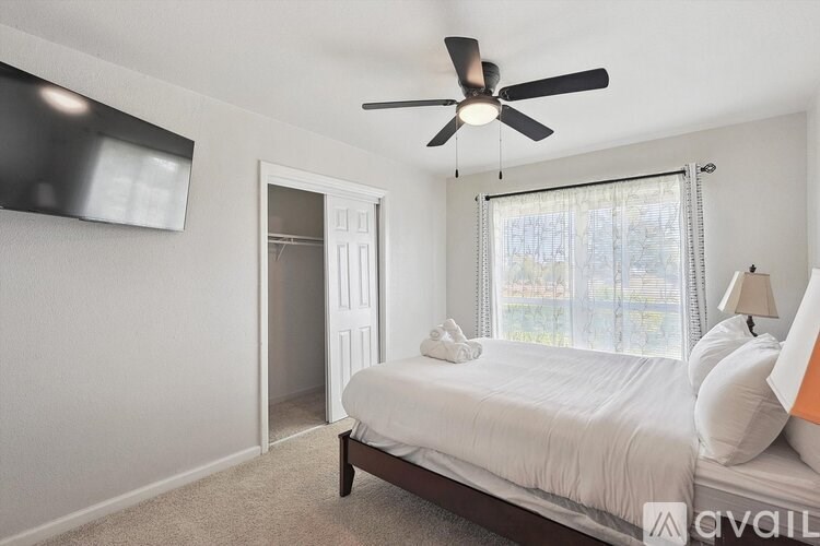 A bedroom with a bed, a ceiling fan, and a window with blinds.