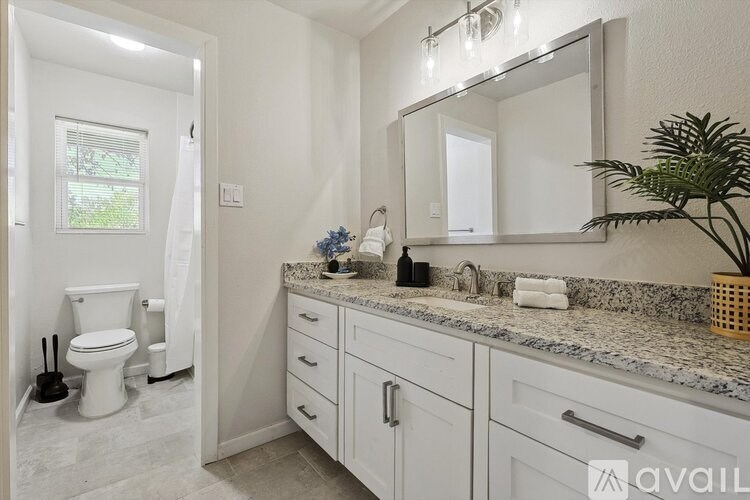 A bathroom with a toilet, sink, and mirror.