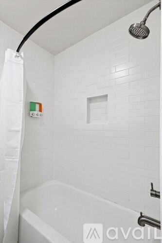 A white bathroom with a shower head and a bathtub.
