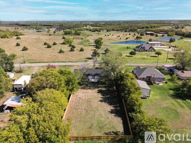 A bird's eye view of a rural landscape with a few houses and a lake.