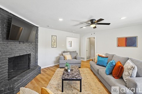 A living room with a grey couch, a coffee table, a fireplace, and a ceiling fan.