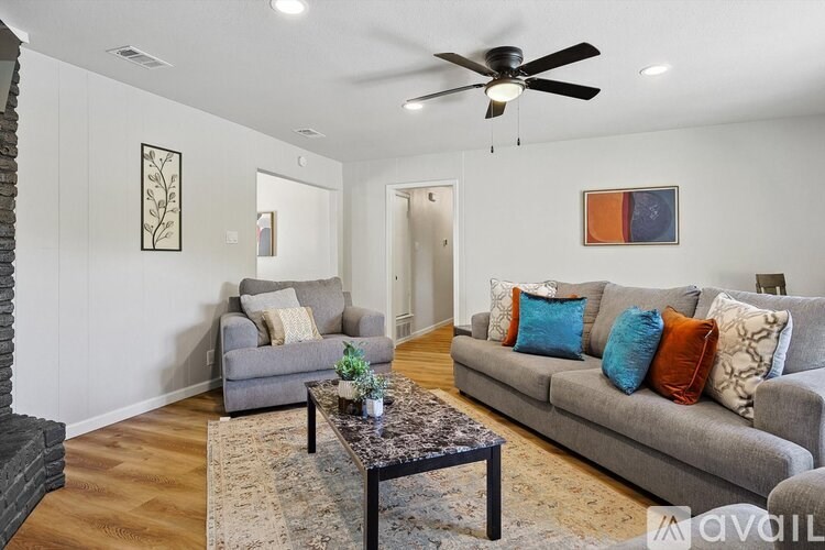 A living room with a grey couch, a coffee table, and a ceiling fan.