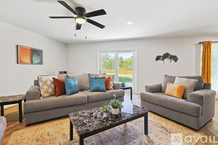A living room with a grey couch, a coffee table, and a ceiling fan.