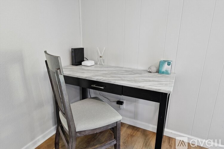 A chair is placed in front of a desk with a computer and some other items on it.