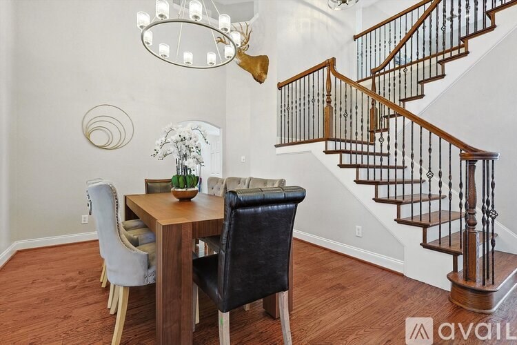 A wooden dining table with four chairs and a chandelier hangs above it.