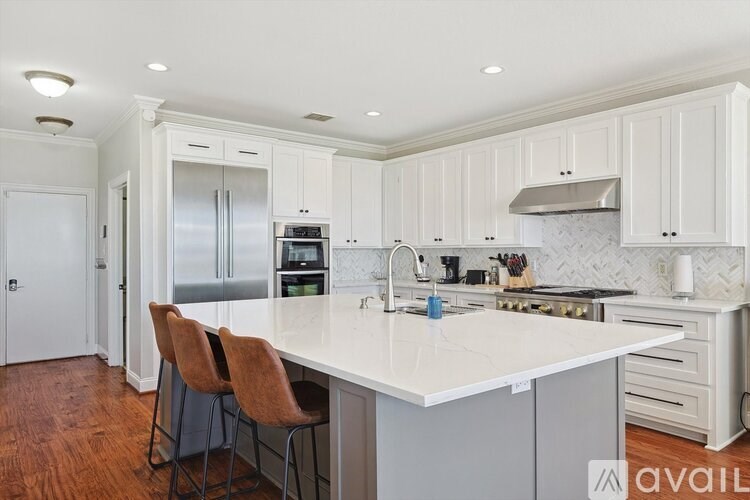 A kitchen with white cabinets and a marble backsplash.
