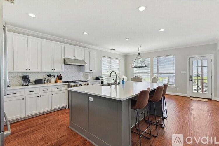 A kitchen with white cabinets and a large island with chairs.