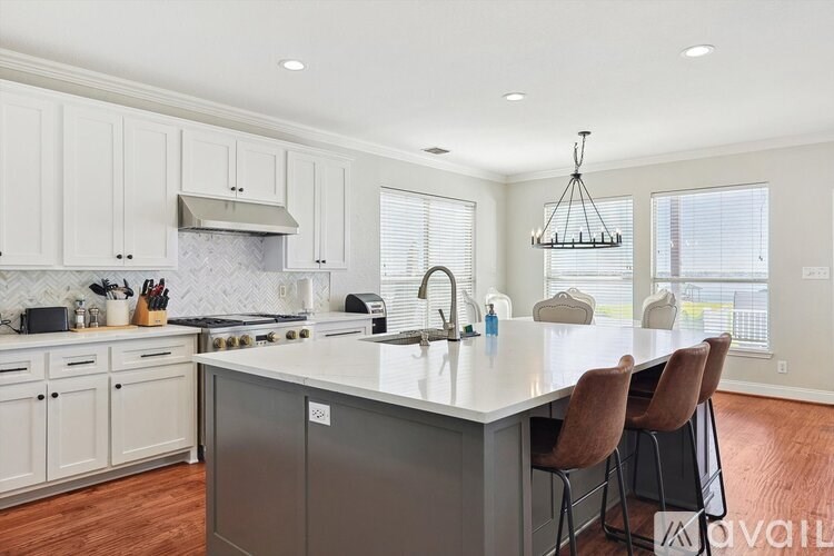 A kitchen with a large island and chairs.