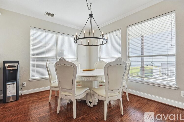 A dining room with a chandelier, four chairs, and a table.