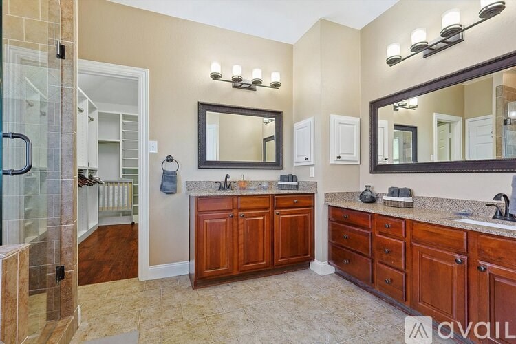 A bathroom with a glass shower stall, double sinks, and a large mirror.