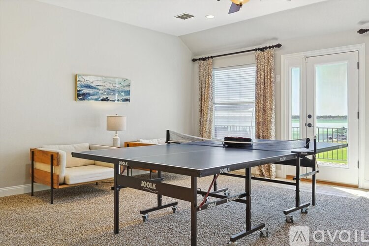 A ping pong table is in the middle of a room with a white couch and a painting on the wall.