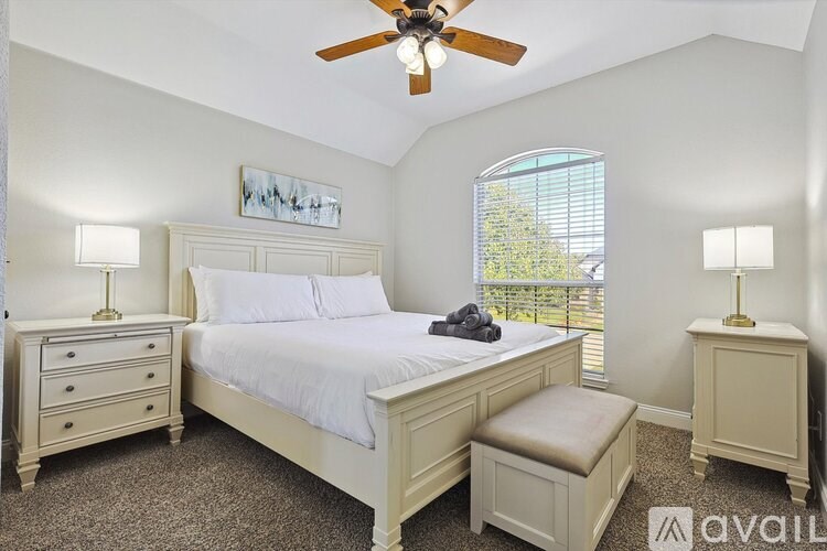 A bedroom with a large bed, two lamps, and a ceiling fan.