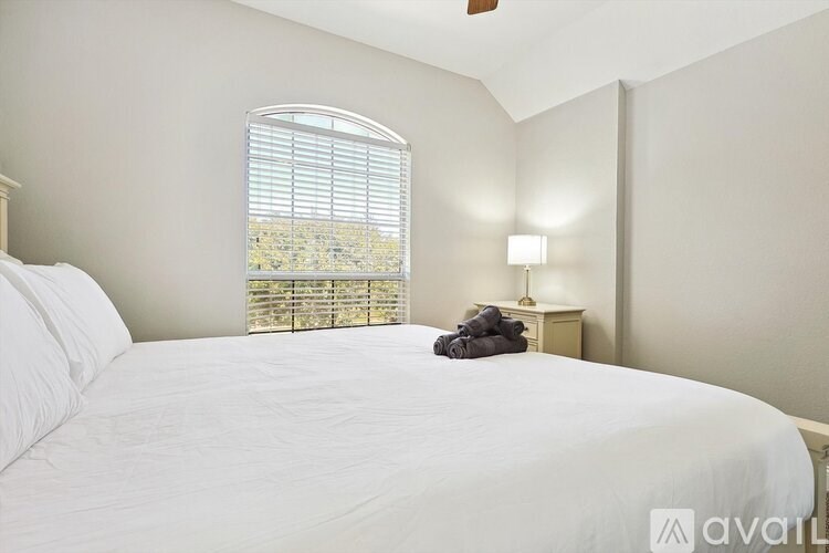 A bedroom with a large bed and a window with blinds.