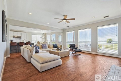 A spacious living room with a white sofa set and a wooden floor.