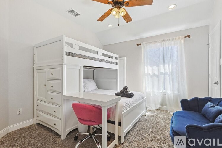 A bedroom with a white bunk bed and a desk with a red chair.