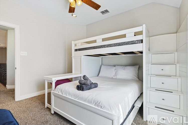 A white bedroom with a bunk bed and a desk.