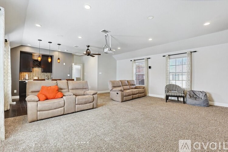 A spacious living room with a grey carpet and a ceiling fan.
